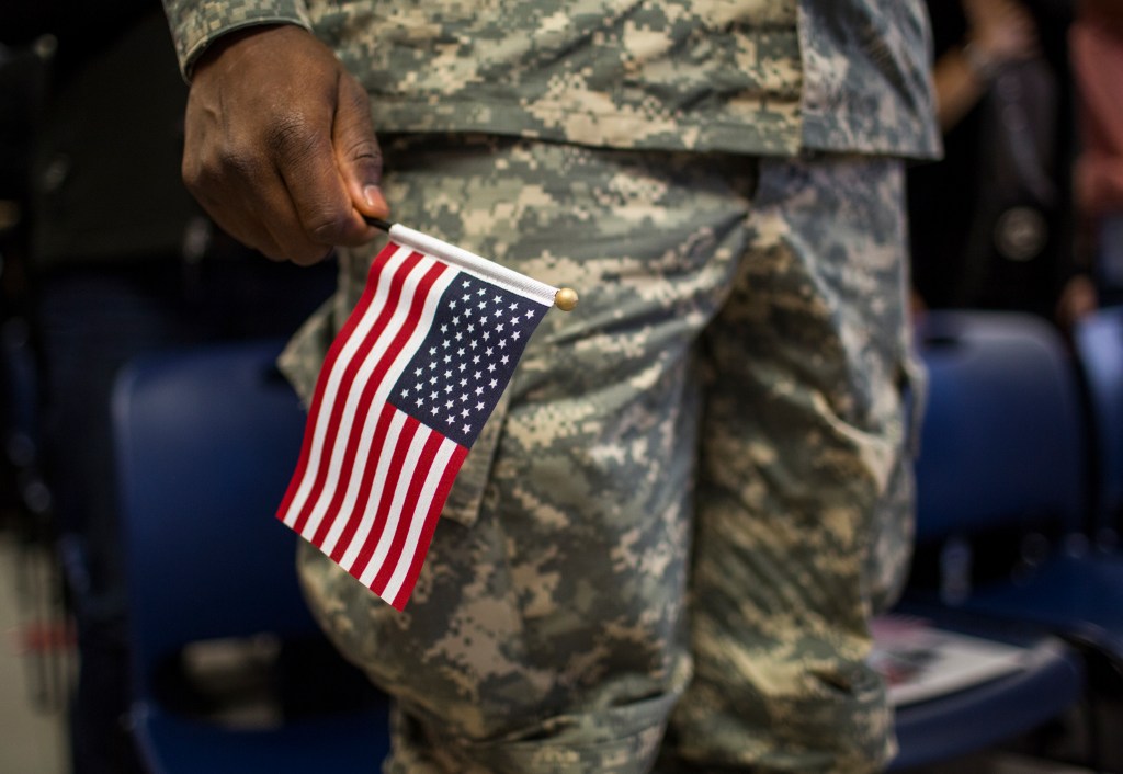 Soldado sostiene bandera de EEUU durante ceremonia de naturalización en NY